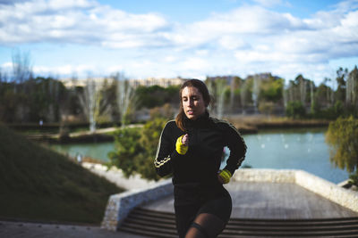 Woman exercising against lake and sky