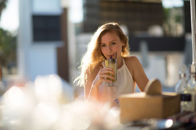 Young woman sitting with drink during sunset