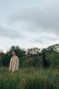 Rear view of man standing on field against sky