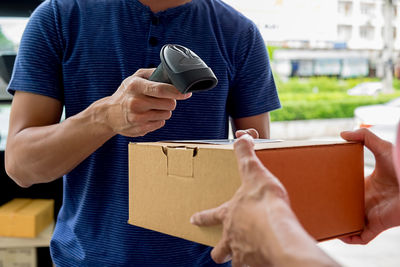 Midsection of delivery man scanning parcel held by customer