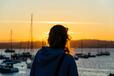 Rear view of woman against sea and sky during sunset