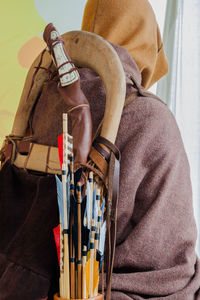 Rear view of man wearing period costume while carrying bow and arrows