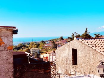 Townscape by sea against clear blue sky