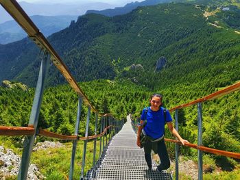 Man on footbridge against mountains