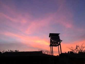 Low angle view of silhouette water tower against sky during sunset