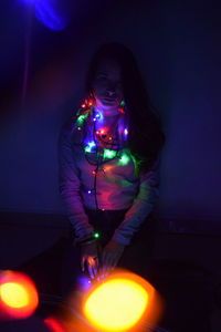 Woman wearing mask against illuminated lights at night