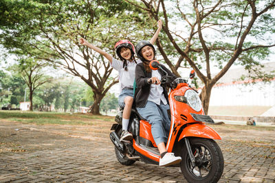 Portrait of young woman riding motor scooter on road