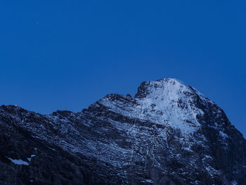 Low angle view of snowcapped mountains against clear sky at blue hour