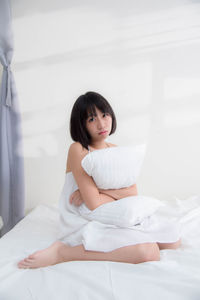 Portrait of a young woman sitting on bed