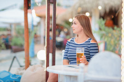 Portrait of woman drinking beer at beach cafe