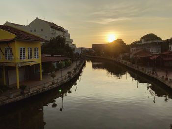 Canal amidst buildings against sky during sunset