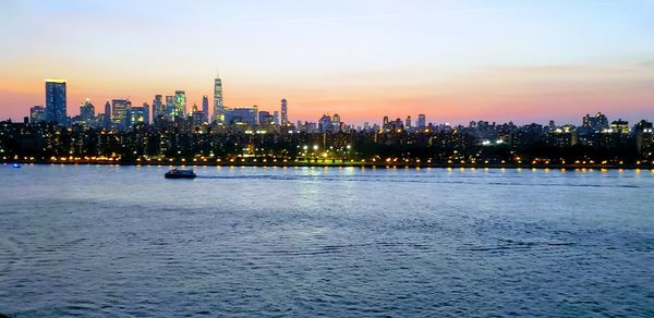 Illuminated buildings in city against sky at sunset