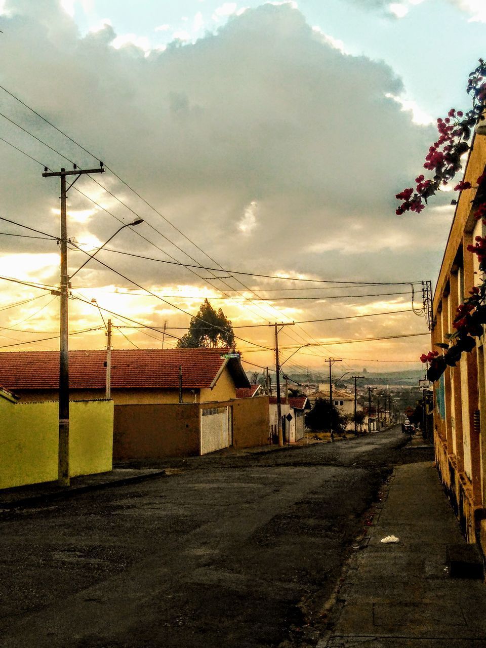 STREET AMIDST BUILDINGS AGAINST SKY DURING SUNSET