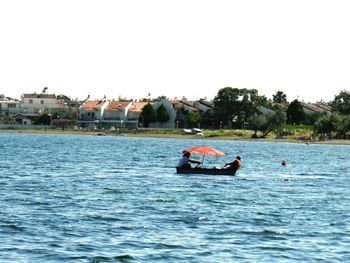 People on boat in sea against clear sky