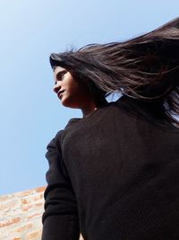 Low angle view of woman looking away against clear sky
