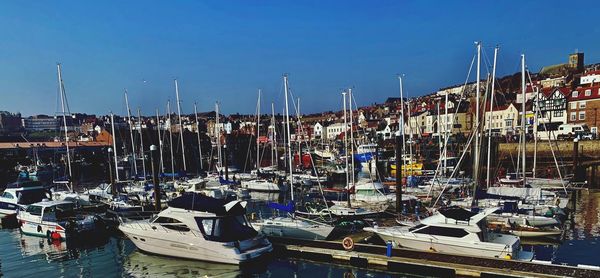 Boats moored in harbor against buildings in city