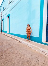 Full length of woman standing against wall