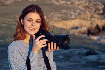 Portrait of smiling young woman holding camera