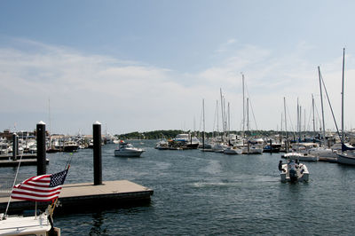 Boats moored at harbor against sky