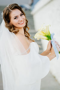 Portrait of smiling young woman holding white rose