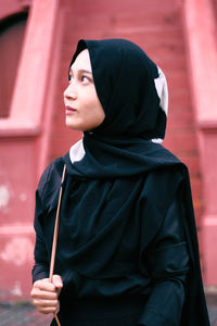 Mid adult man looking away while standing against red wall
