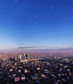 High angle view of illuminated cityscape against clear blue sky