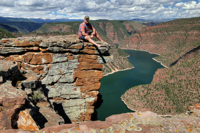 Rear view of man sitting on rock