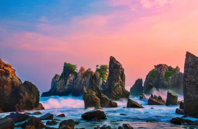 Rocks on sea against sky during sunset