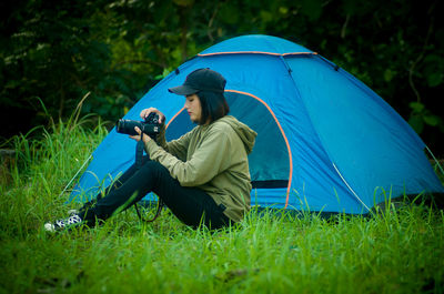 Man photographing with camera while sitting on grass