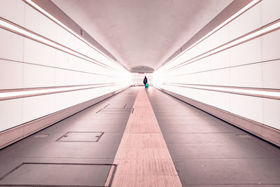 Rear view of people walking on illuminated corridor