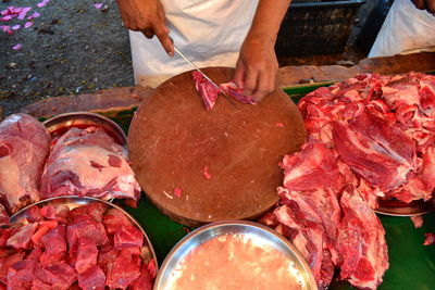 Midsection of man cutting meat at table