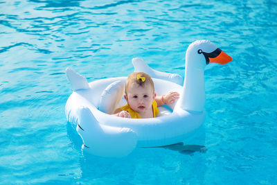 Cute baby sitting on inflatable swan in pool