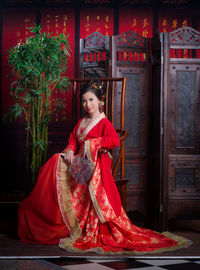 Portrait of smiling young woman standing against red wall