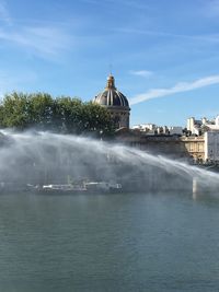 Water spraying over river in city