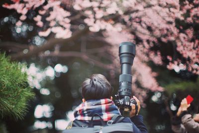 Close-up of man holding camera against trees