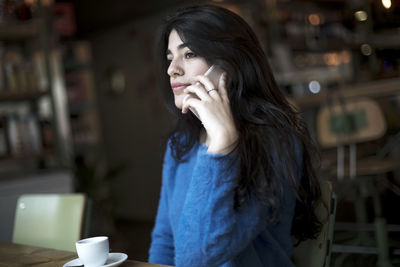 Young woman looking away while standing in cafe