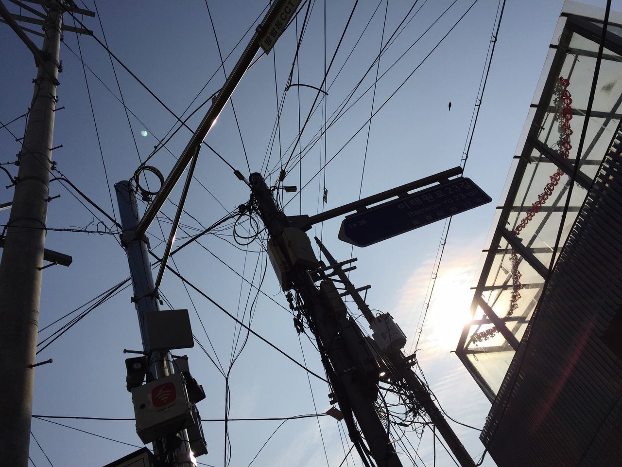 low angle view, power line, power supply, electricity, fuel and power generation, electricity pylon, technology, clear sky, cable, sky, communication, building exterior, blue, built structure, day, outdoors, connection, construction site, no people, crane - construction machinery