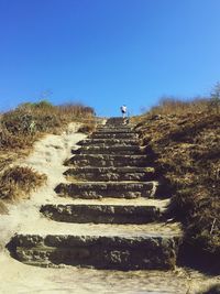 Steps on landscape against clear blue sky