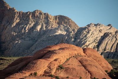 Landscape of people on rock formation, white hills in the back in snow canyon state park in utah