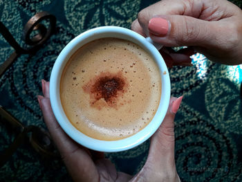 High angle view of hand holding coffee cup