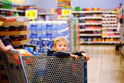 Portrait of boy sitting in shopping cart at store