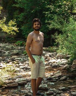 Portrait of shirtless man standing on rock