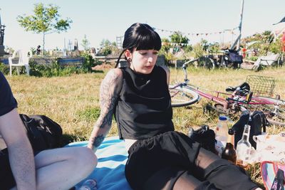 Portrait of goth woman sitting on field against clear sky