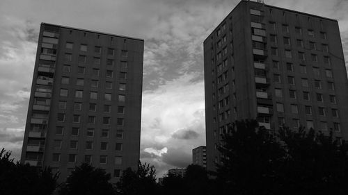 Low angle view of skyscrapers against cloudy sky