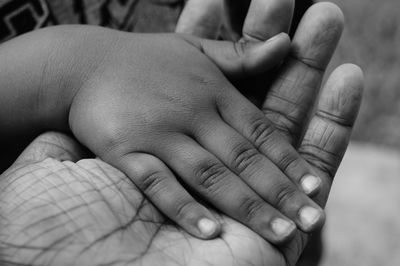 Close-up of father holding baby hand