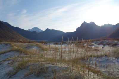 Scenic view of sand dunes and mountains against sky