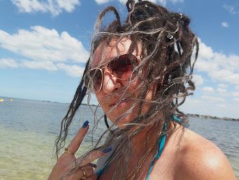 Woman with messy hair gesturing peace sign at beach