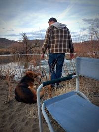 Rear view of man with dog against sky