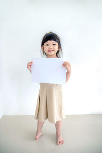 Portrait of smiling girl standing against wall
