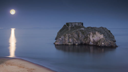 Rock formation on beach against sky